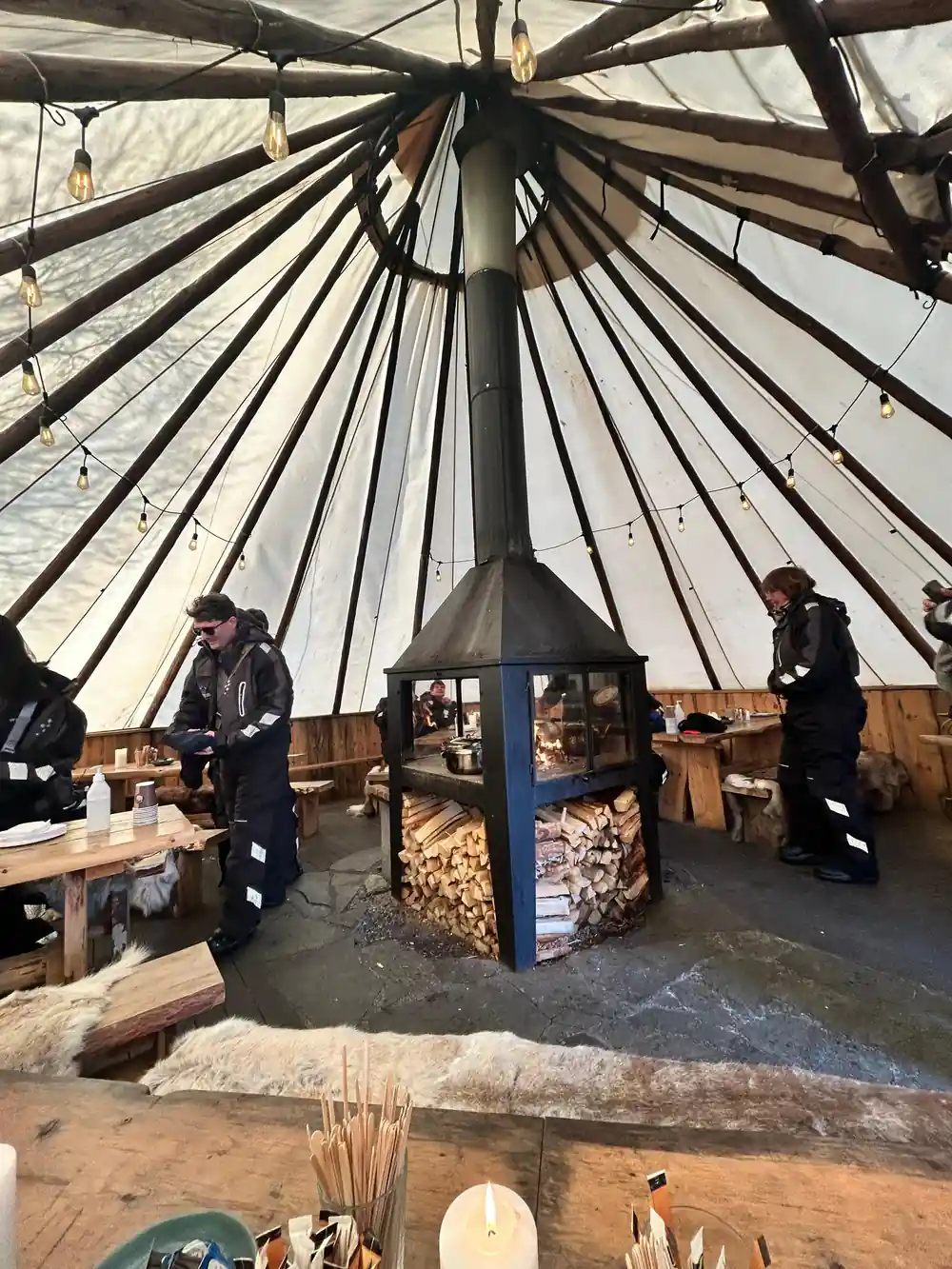 Interior of conical tent with central stove and benches