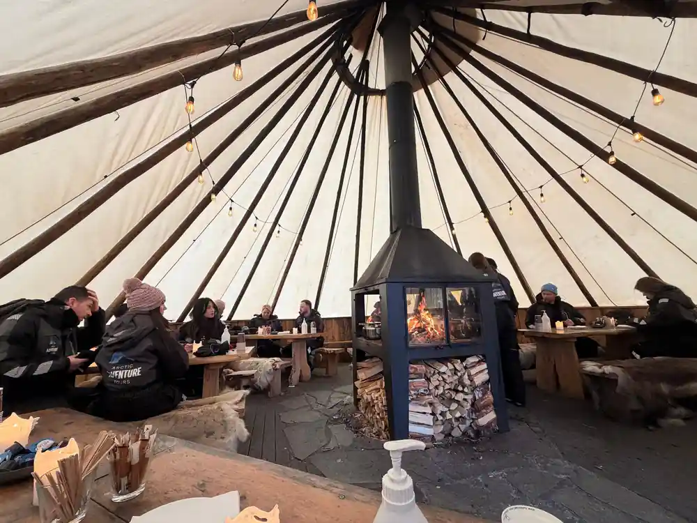 Interior of Sami tent with central fire, seated people
