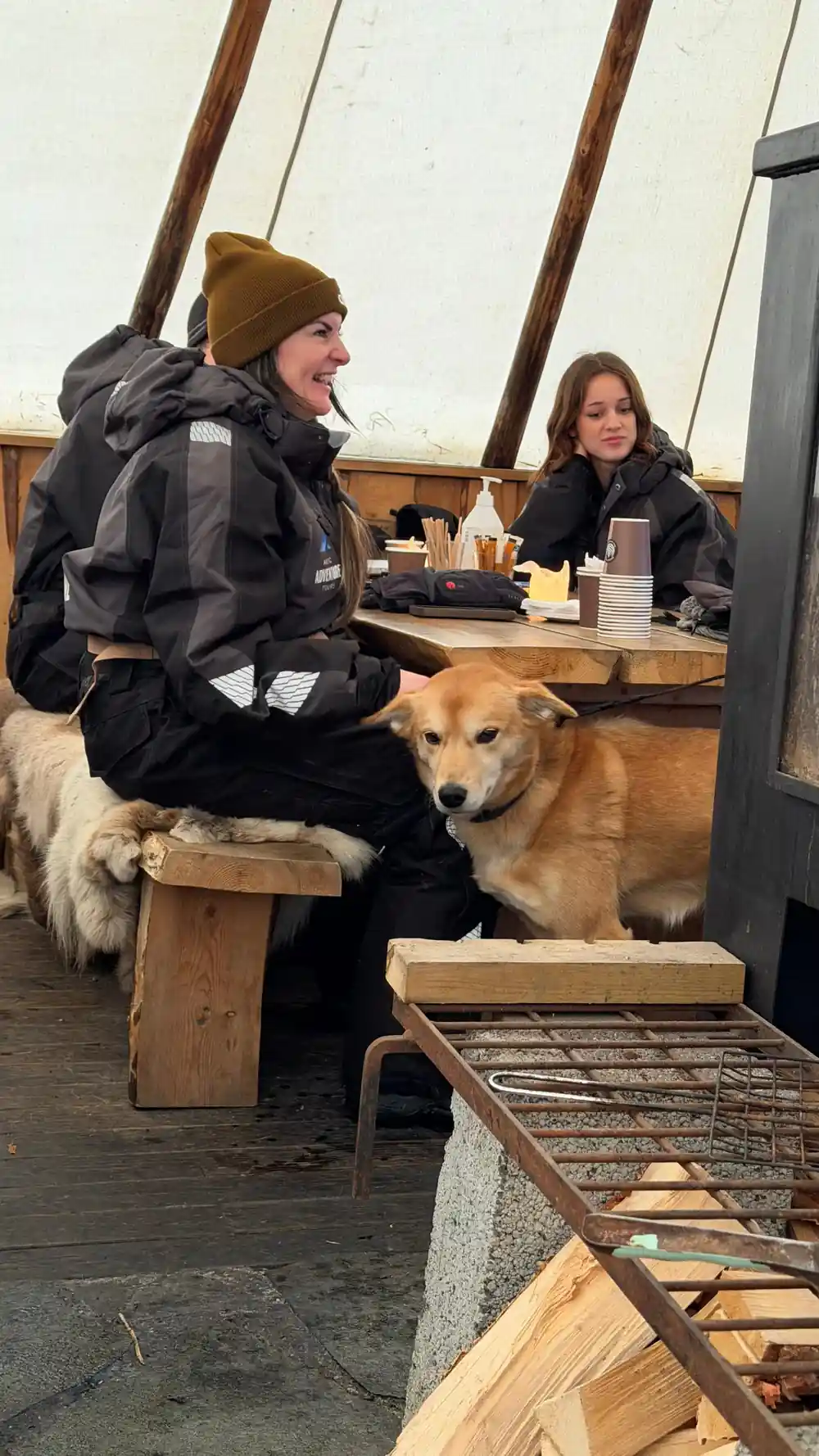 People sitting inside tepee tent with dog at table
