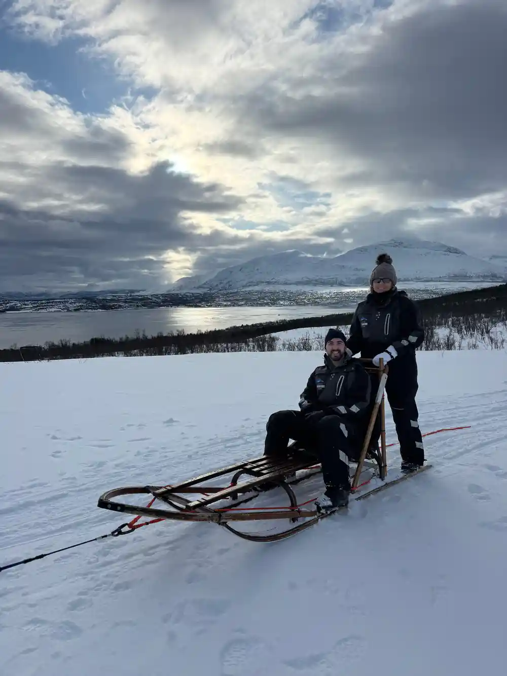 Woman and child with dog sled in snowy landscape