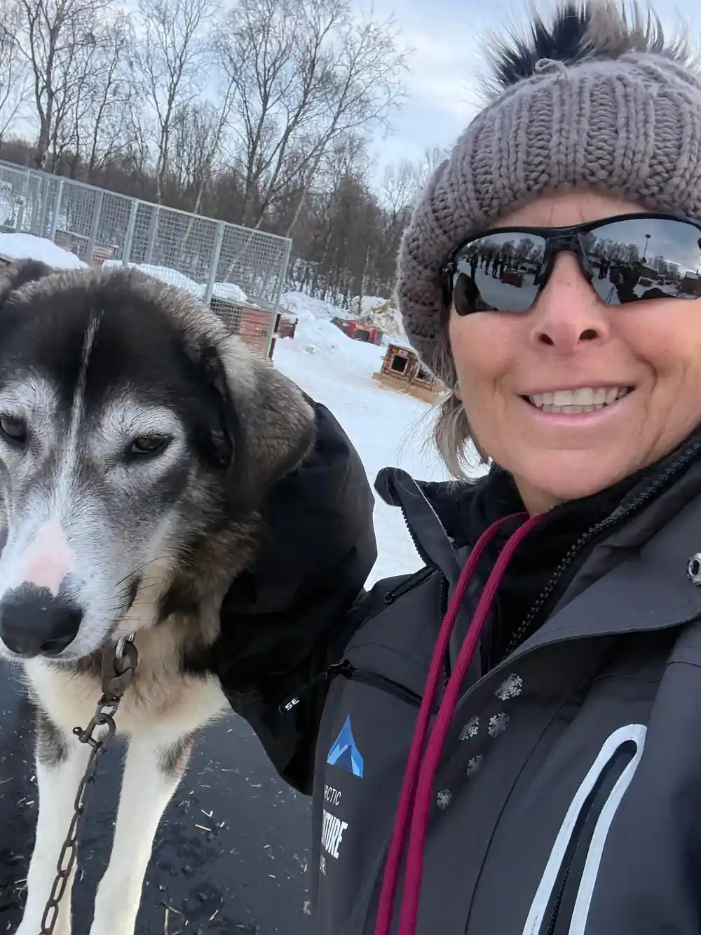 Woman with husky dog wearing sunglasses and winter hat